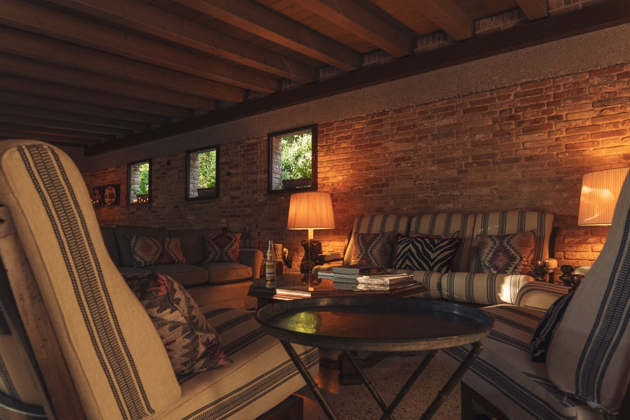 Salottino privato con divani a righe, cuscini kilim e luce calda